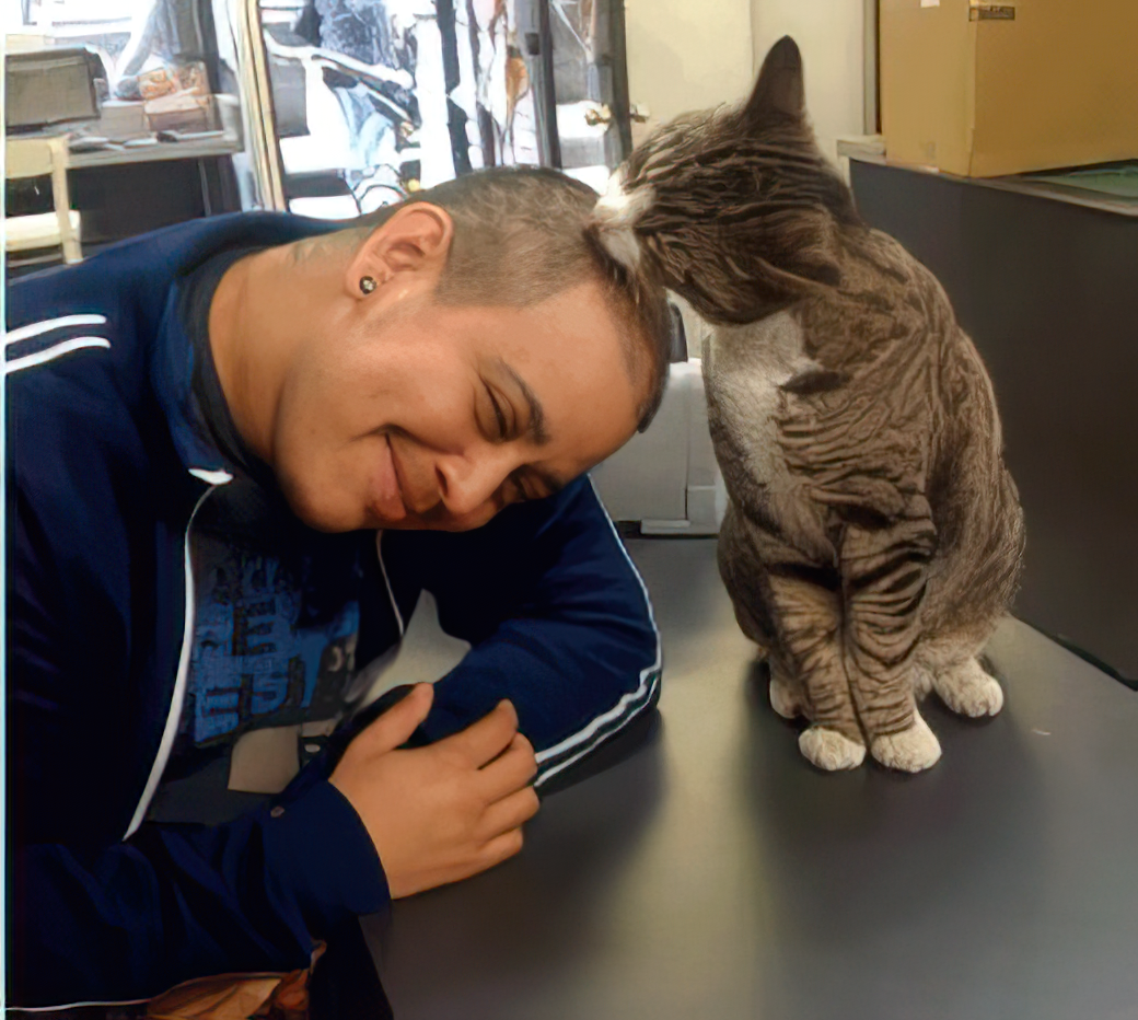 A person with short hair and cat sitting at a table